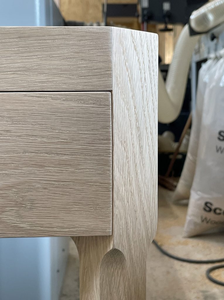 Edge of drawer front blending into angled leg.
