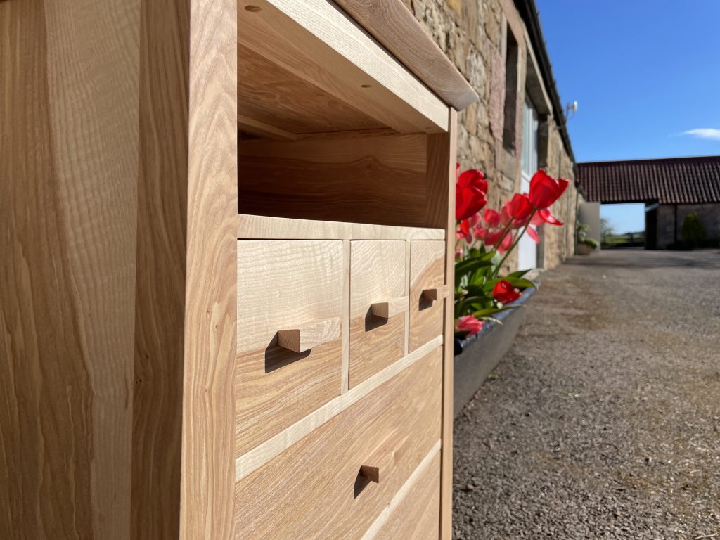 Picture of a "Chaffinch" Bedside Cabinet in olive ash.  Bespoke furniture made by Iain Stirling of Chapelhill Fine Furniture.