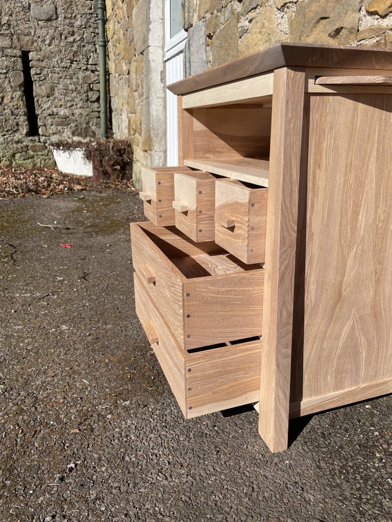 Picture of a "Chaffinch" Bedside Cabinet in olive ash.  Bespoke furniture made by Iain Stirling of Chapelhill Fine Furniture.