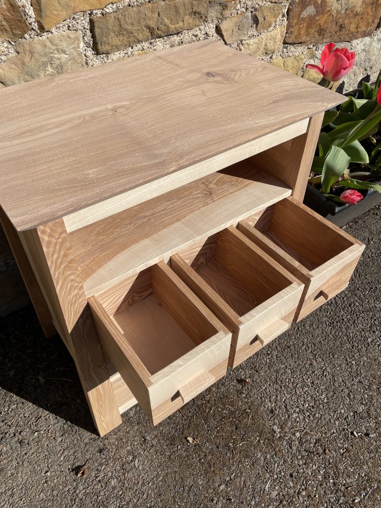 Picture of a "Chaffinch" Bedside Cabinet in olive ash.  Bespoke furniture made by Iain Stirling of Chapelhill Fine Furniture.