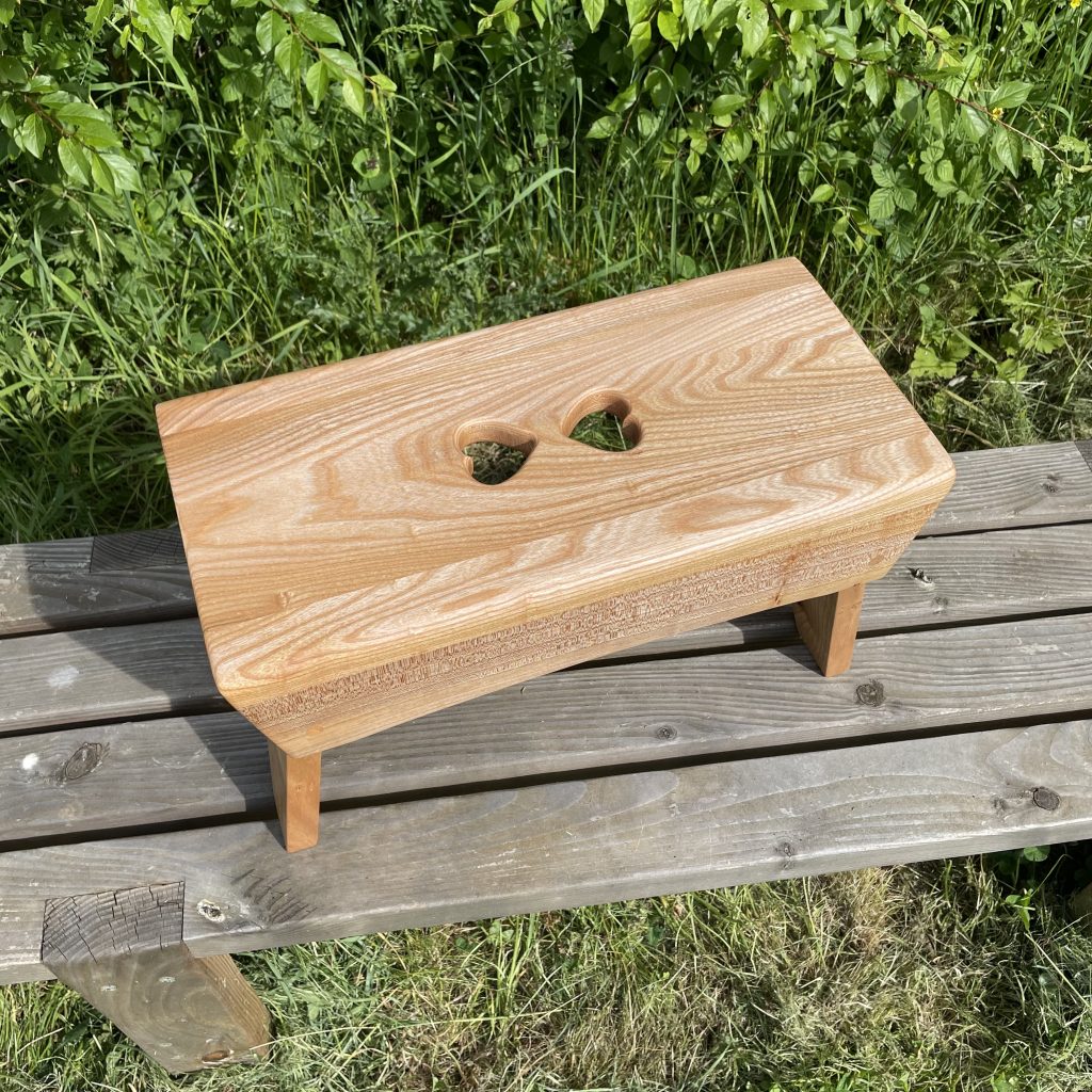 Scottish creepie stool in elm, with double-heart finger holes, made by Chapelhill Fine Furniture.
