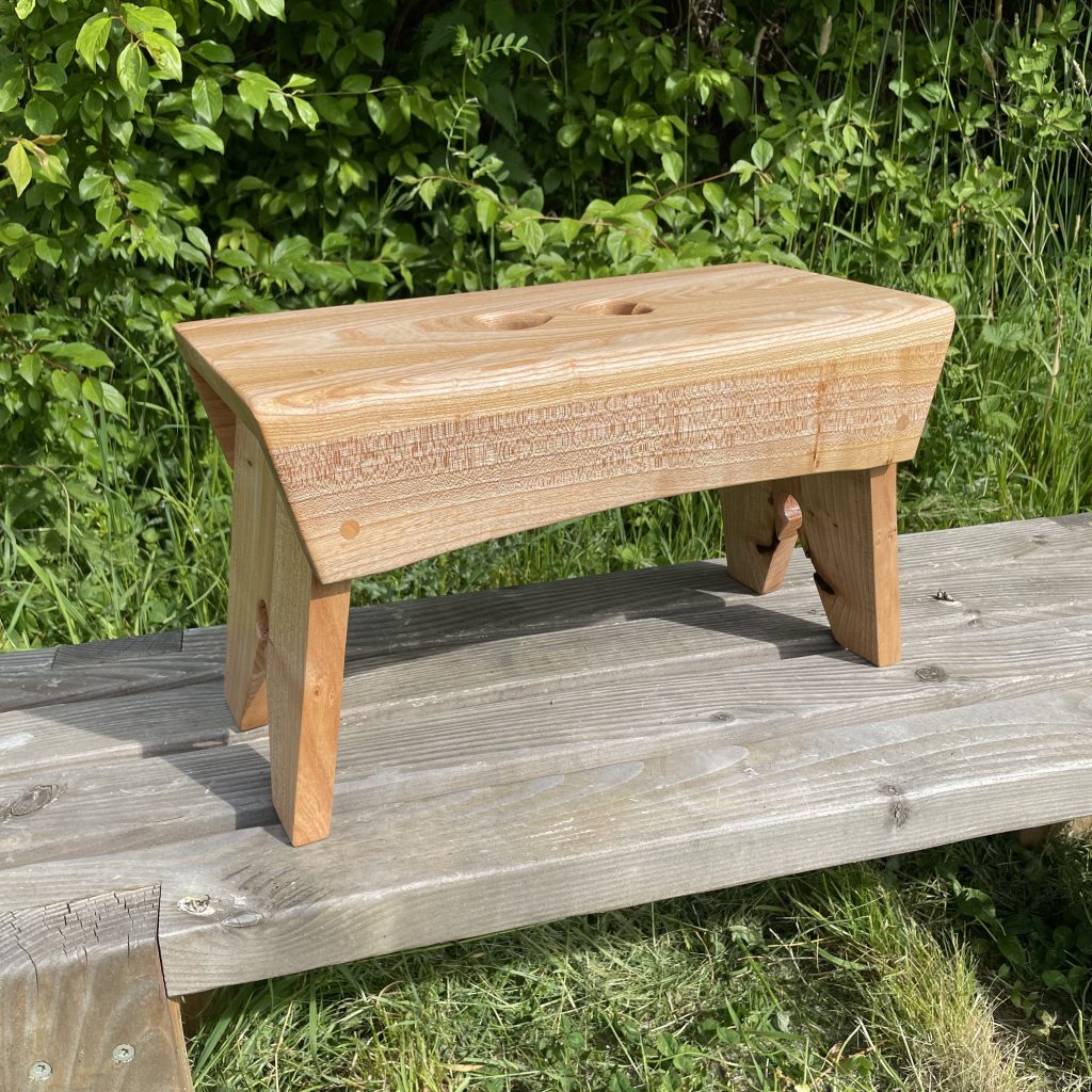 Scottish creepie stool in elm, with double-heart finger holes, made by Chapelhill Fine Furniture.