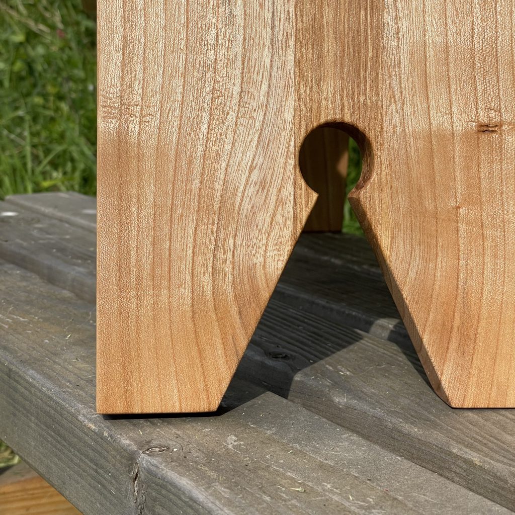 Scottish creepie stool in elm, with double-heart finger holes, made by Chapelhill Fine Furniture.